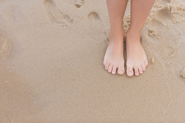 Child standing barefoot in sand