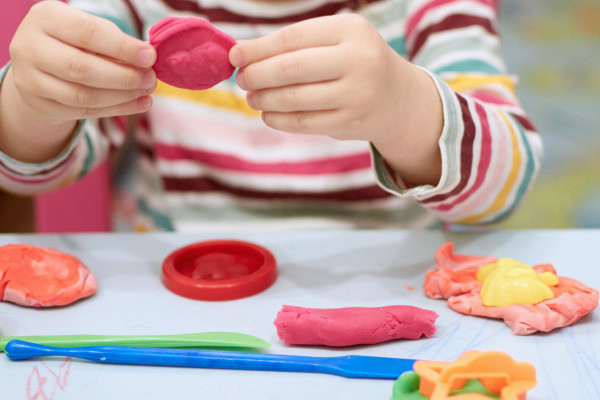 Child in colourful striped shirt playing with play dough